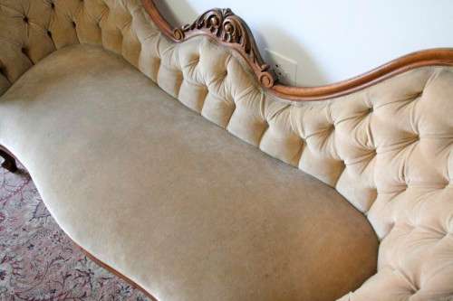 A beautiful, elegant carved Victorian sofa with deep button detailing and beige fabric.