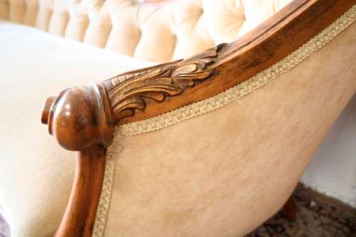 A beautiful, elegant carved Victorian sofa with deep button detailing and beige fabric.