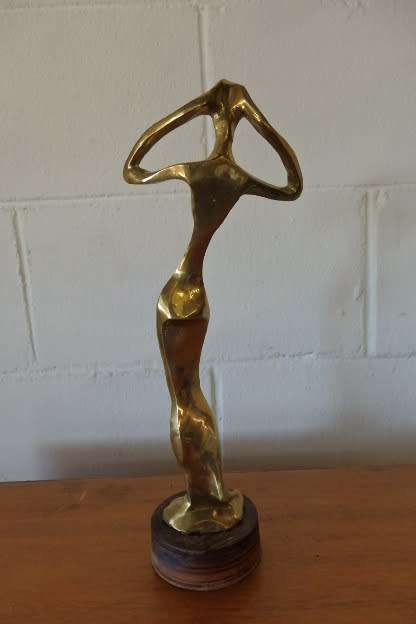 A beautiful tall ornamental brass abstract figurine on a wooden stand in wonderful condition