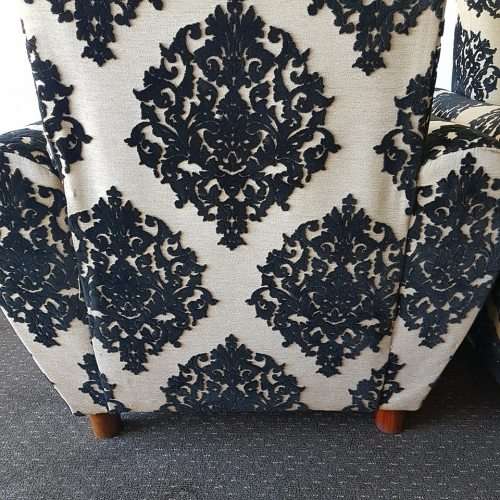 A one seater sofa chair upholstered in a stunning brocade fabric with wooden legs