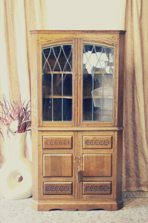 An exquisite vintage solid oak corner display cabinet with lead glass doors and a large cupboard.