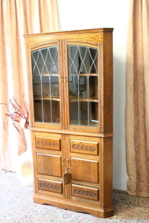 An exquisite vintage solid oak corner display cabinet with lead glass doors and a large cupboard.