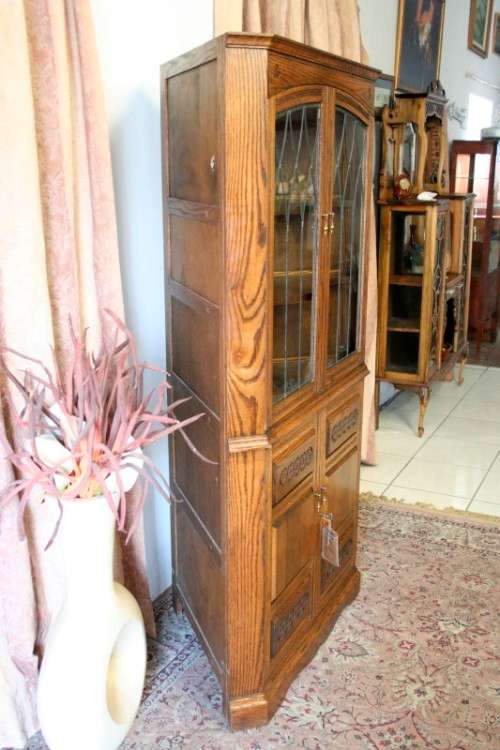 An exquisite vintage solid oak corner display cabinet with lead glass doors and a large cupboard.