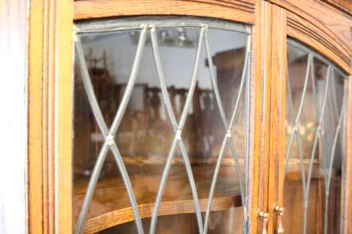 An exquisite vintage solid oak corner display cabinet with lead glass doors and a large cupboard.