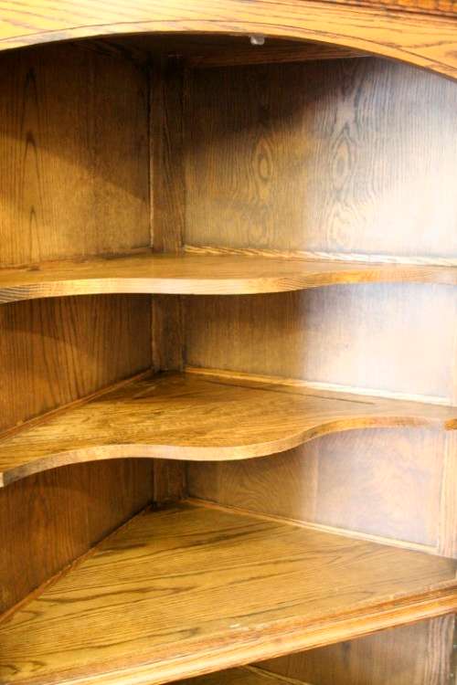 An exquisite vintage solid oak corner display cabinet with lead glass doors and a large cupboard.