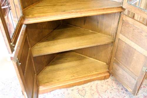An exquisite vintage solid oak corner display cabinet with lead glass doors and a large cupboard.