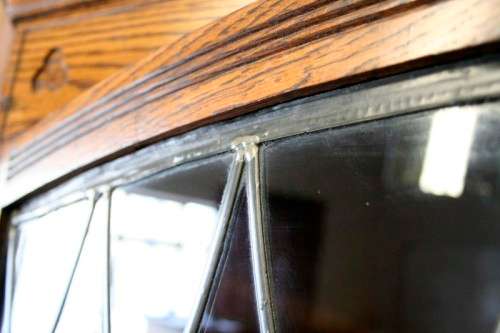 An exquisite vintage solid oak corner display cabinet with lead glass doors and a large cupboard.