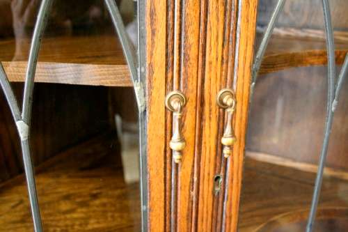An exquisite vintage solid oak corner display cabinet with lead glass doors and a large cupboard.