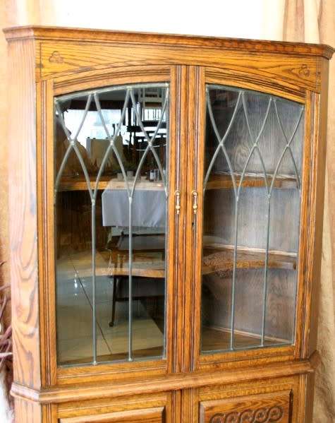 An exquisite vintage solid oak corner display cabinet with lead glass doors and a large cupboard.