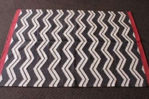 A beautifully made black and white "flat-weave" wool carpet with red edges in stunning condition