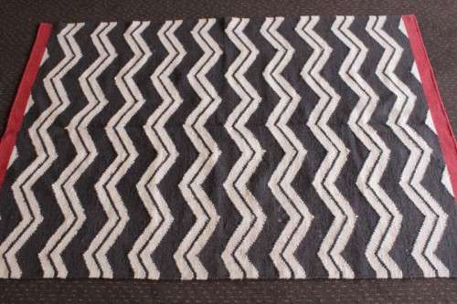 A beautifully made black and white "flat-weave" wool carpet with red edges in stunning condition