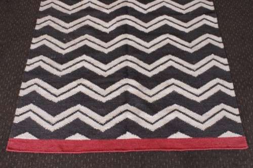 A beautifully made black and white "flat-weave" wool carpet with red edges in stunning condition