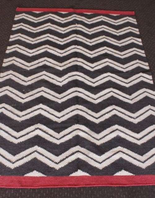 A beautifully made black and white "flat-weave" wool carpet with red edges in stunning condition