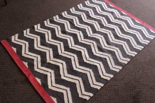 A beautifully made black and white "flat-weave" wool carpet with red edges in stunning condition
