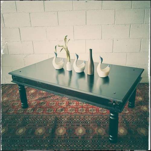 A stunning Indonesian Teak coffee table with clean lines, thick turned legs and carved detailing