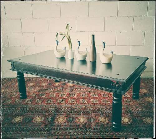 A stunning Indonesian Teak coffee table with clean lines, thick turned legs and carved detailing