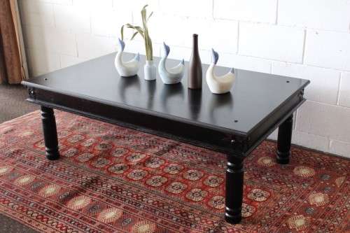A stunning Indonesian Teak coffee table with clean lines, thick turned legs and carved detailing
