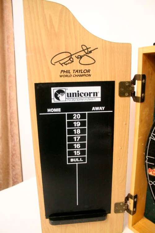 A top quality Unicorn (Phil Taylor)dart board in a wooden cabinet w score boards in super condition.
