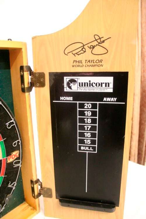 A top quality Unicorn (Phil Taylor)dart board in a wooden cabinet w score boards in super condition.