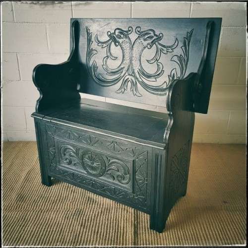 A superb antique hand-carved blackened oak monks bench with a storage chest in the base