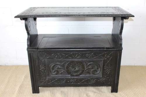 A superb antique hand-carved blackened oak monks bench with a storage chest in the base