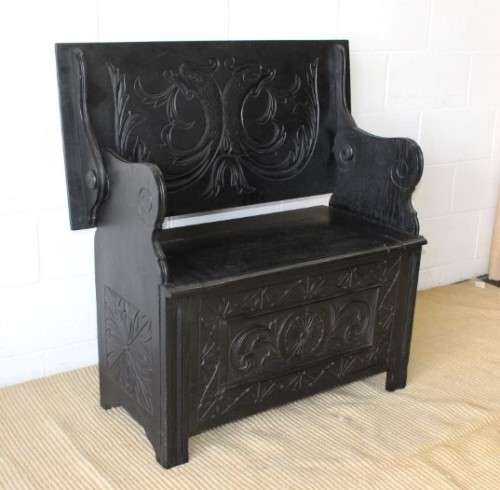 A superb antique hand-carved blackened oak monks bench with a storage chest in the base