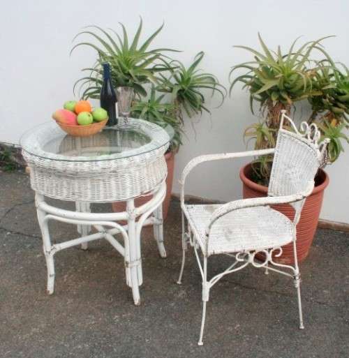 A wonderful white wicker table with a glass top and a chair all weather outdoor/ patio set.