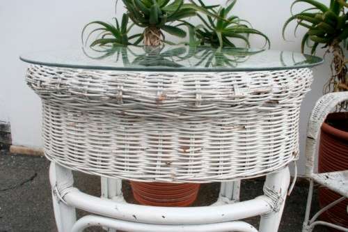 A wonderful white wicker table with a glass top and a chair all weather outdoor/ patio set.