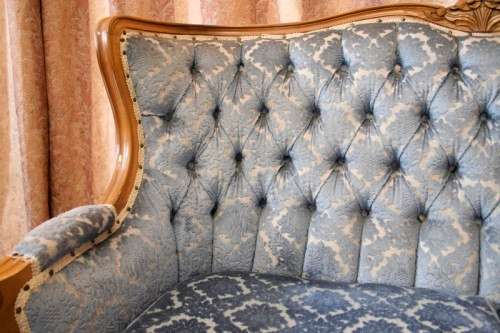 2 beautiful, elegant carved Victorian sofas with deep button detailing and blue period style fabric.