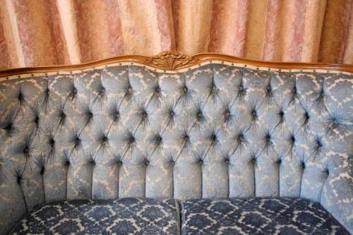 2 beautiful, elegant carved Victorian sofas with deep button detailing and blue period style fabric.