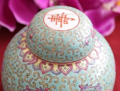A beautiful and detailed jade-green oriental ginger jar & lid with hand painted symbols and flowers