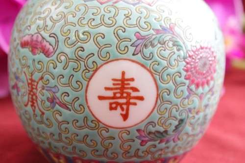 A beautiful and detailed jade-green oriental ginger jar & lid with hand painted symbols and flowers