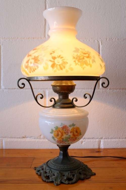 A stunning vintage milk-glass table lamp with floral transfer work on a brass tone metal base
