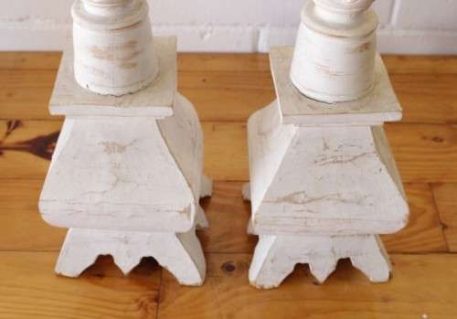 A pair of tall white chalk-painted carved wooden candle stands - perfect ambience lighting