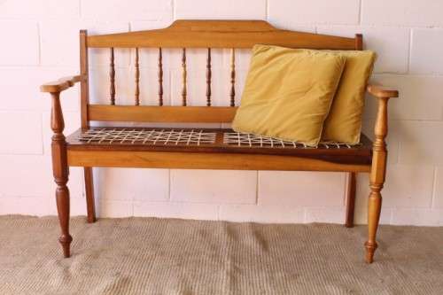 A beautifully made solid yellowwood two-seater riempie bench with two gold cushions
