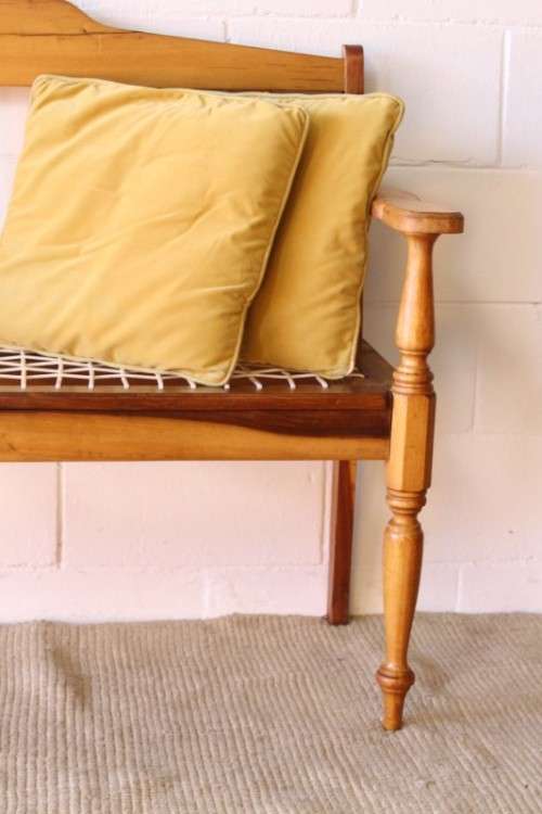 A beautifully made solid yellowwood two-seater riempie bench with two gold cushions