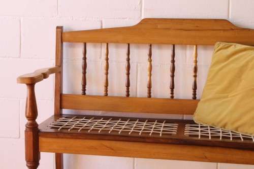 A beautifully made solid yellowwood two-seater riempie bench with two gold cushions