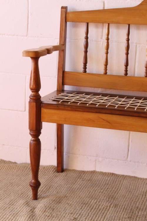 A beautifully made solid yellowwood two-seater riempie bench with two gold cushions