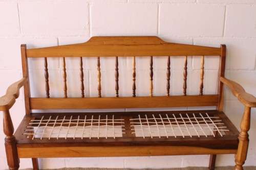A beautifully made solid yellowwood two-seater riempie bench with two gold cushions