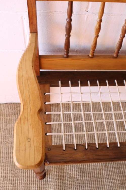 A beautifully made solid yellowwood two-seater riempie bench with two gold cushions