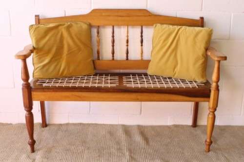 A beautifully made solid yellowwood two-seater riempie bench with two gold cushions