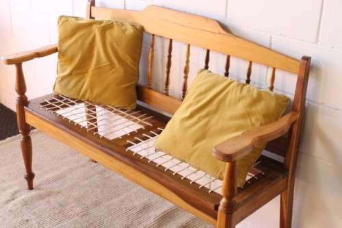 A beautifully made solid yellowwood two-seater riempie bench with two gold cushions