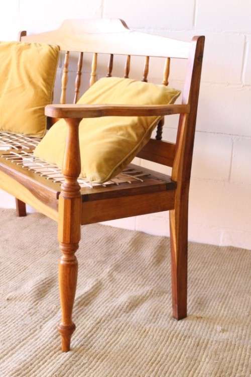 A beautifully made solid yellowwood two-seater riempie bench with two gold cushions