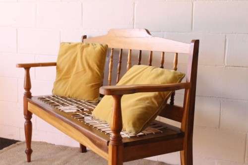 A beautifully made solid yellowwood two-seater riempie bench with two gold cushions