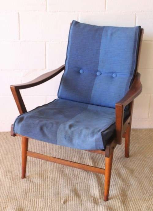 A fabulous mid-century solid teak armchair with sprung seat and backrest and blue fabric cushions