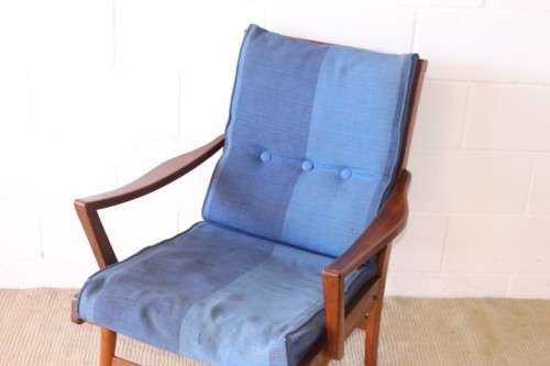 A fabulous mid-century solid teak armchair with sprung seat and backrest and blue fabric cushions