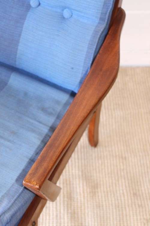 A fabulous mid-century solid teak armchair with sprung seat and backrest and blue fabric cushions