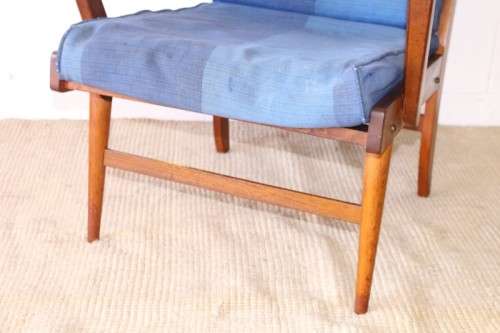 A fabulous mid-century solid teak armchair with sprung seat and backrest and blue fabric cushions