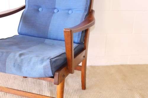 A fabulous mid-century solid teak armchair with sprung seat and backrest and blue fabric cushions