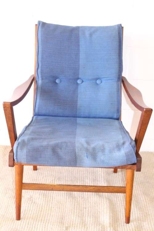 A fabulous mid-century solid teak armchair with sprung seat and backrest and blue fabric cushions